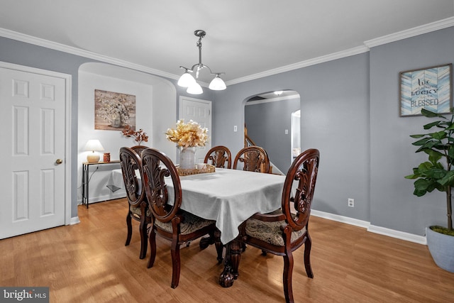 dining area featuring a chandelier, ornamental molding, and light hardwood / wood-style flooring