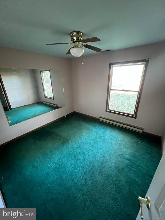 bonus room featuring dark carpet, a healthy amount of sunlight, and a baseboard heating unit