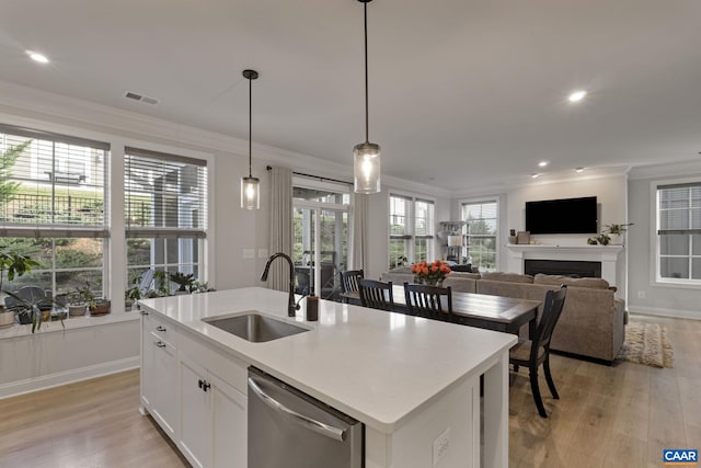 kitchen with dishwasher, a center island with sink, light hardwood / wood-style floors, and white cabinets