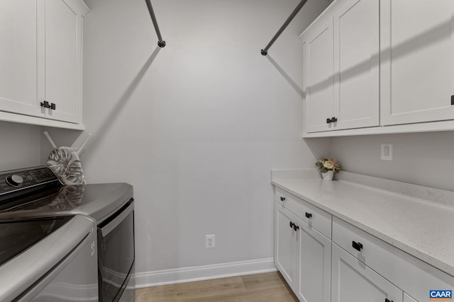 washroom featuring cabinets, washing machine and dryer, and light wood-type flooring