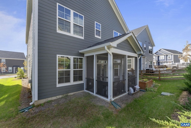 back of property with a sunroom and a yard