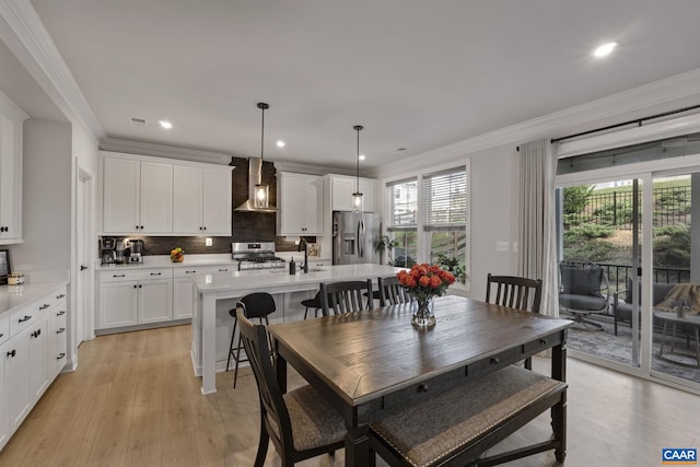 dining area with ornamental molding and light hardwood / wood-style flooring