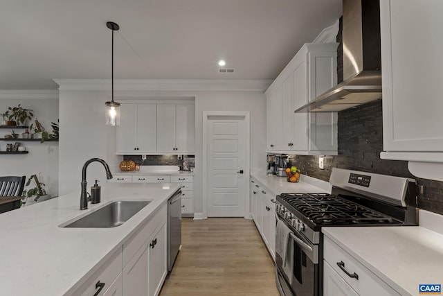 kitchen with stainless steel appliances, white cabinetry, wall chimney range hood, sink, and light hardwood / wood-style flooring