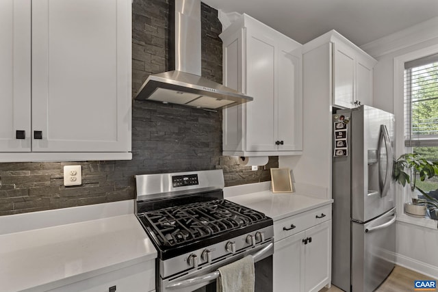 kitchen featuring stainless steel appliances, white cabinets, decorative backsplash, hardwood / wood-style flooring, and wall chimney range hood