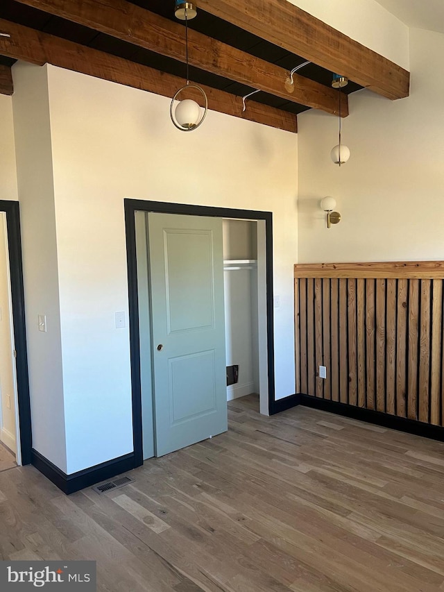 interior space featuring beamed ceiling, wood-type flooring, and a closet