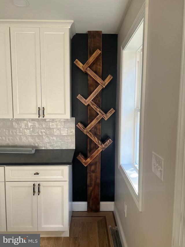 interior space featuring decorative backsplash, hardwood / wood-style floors, and white cabinetry