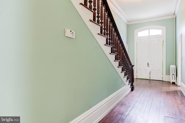 foyer entrance featuring wood-type flooring, radiator heating unit, and ornamental molding