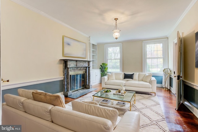 living room featuring a high end fireplace, wood-type flooring, built in shelves, and ornamental molding