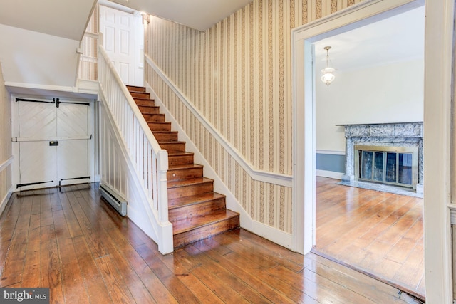 staircase with a high end fireplace and hardwood / wood-style floors