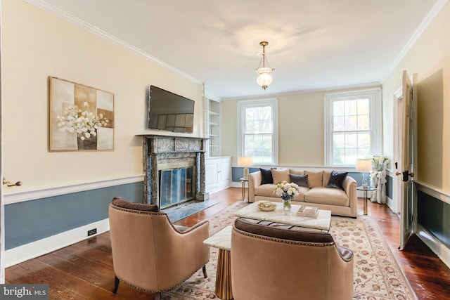 living room featuring built in shelves, crown molding, a high end fireplace, and dark hardwood / wood-style floors