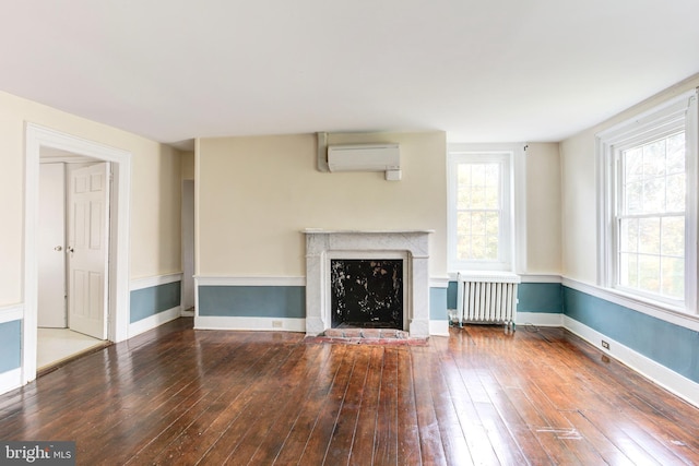 unfurnished living room featuring hardwood / wood-style flooring, a wall unit AC, and radiator