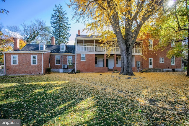 back of house featuring a balcony and a yard