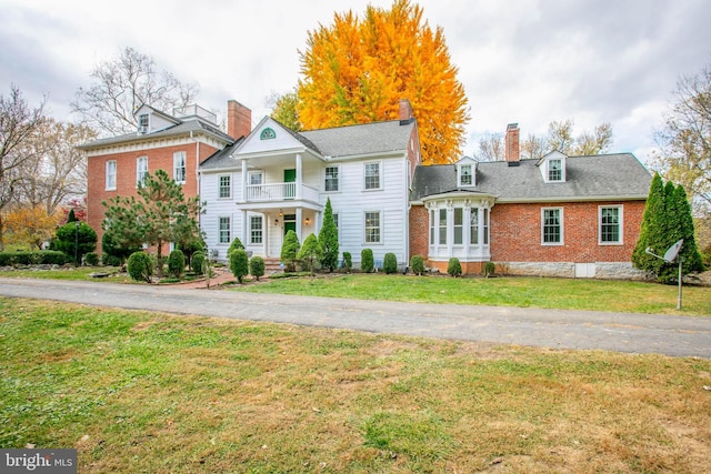 view of front facade featuring a balcony and a front lawn