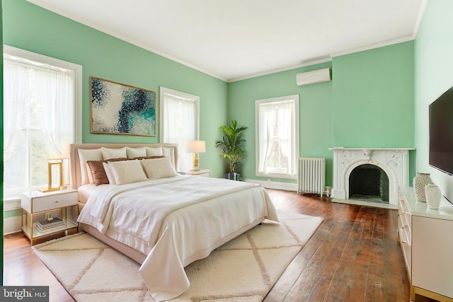 bedroom featuring radiator, a wall mounted air conditioner, a high end fireplace, crown molding, and hardwood / wood-style floors