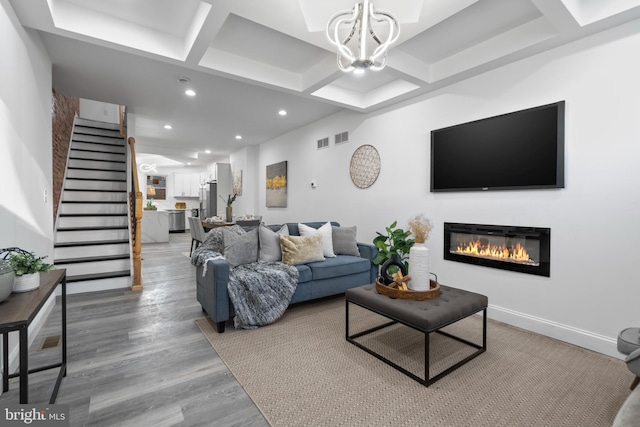 living room with an inviting chandelier, coffered ceiling, hardwood / wood-style floors, and beam ceiling