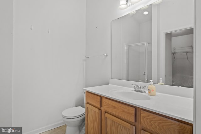 bathroom featuring tile patterned flooring, vanity, toilet, and walk in shower