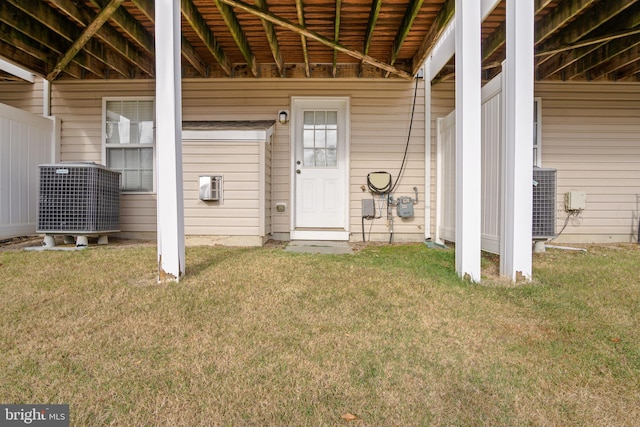 doorway to property with central AC unit and a lawn