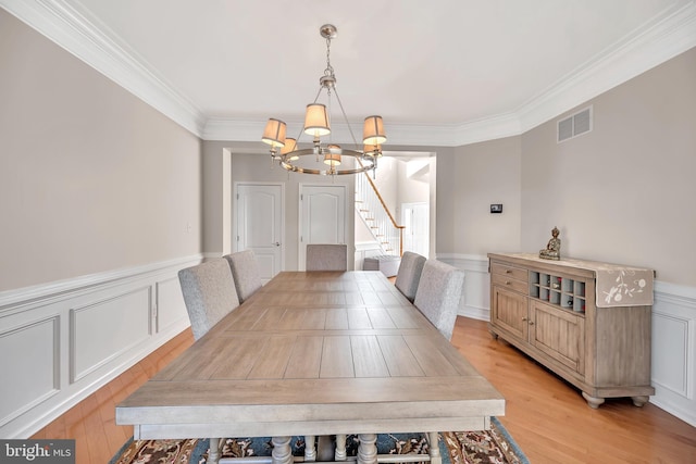 dining area featuring ornamental molding, light hardwood / wood-style flooring, and a notable chandelier