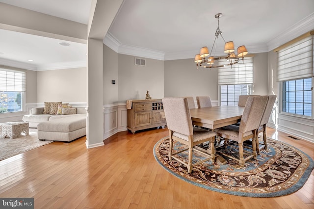 dining space featuring light wood-type flooring, a notable chandelier, and ornamental molding