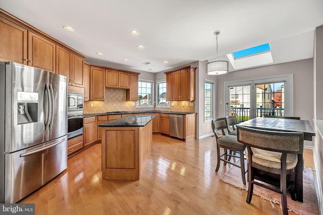 kitchen featuring pendant lighting, stainless steel appliances, light hardwood / wood-style floors, and a skylight