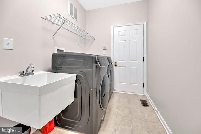 laundry room featuring light tile patterned flooring, separate washer and dryer, and sink