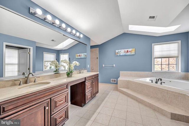 bathroom with vanity, a healthy amount of sunlight, vaulted ceiling, and tiled tub