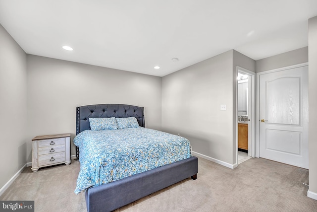 bedroom with ensuite bath and light carpet