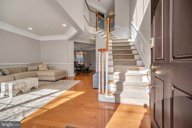 entrance foyer featuring ornamental molding, light hardwood / wood-style flooring, and a notable chandelier