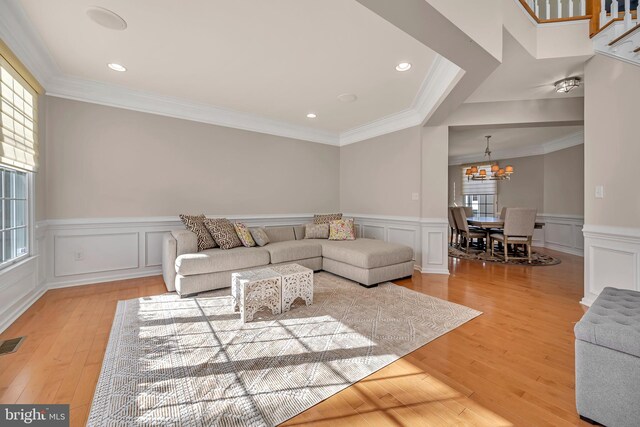 living room with ornamental molding, light hardwood / wood-style flooring, and a chandelier