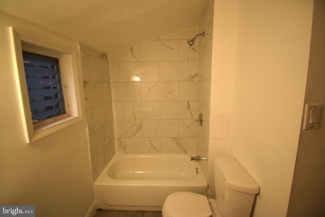 bathroom featuring tiled shower / bath, lofted ceiling, and toilet