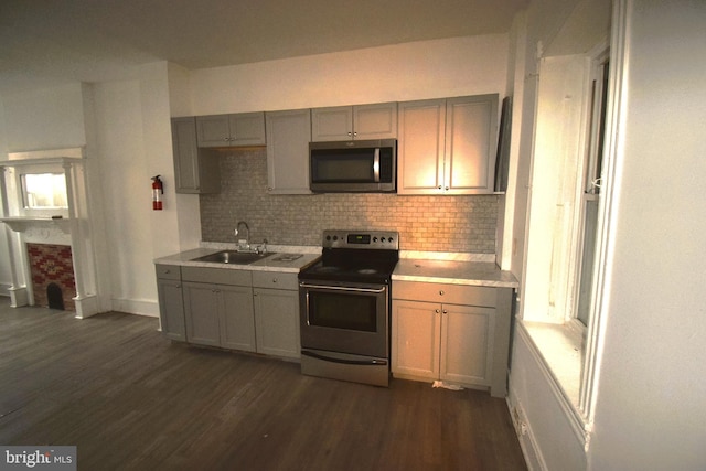 kitchen with sink, dark hardwood / wood-style flooring, backsplash, gray cabinets, and appliances with stainless steel finishes