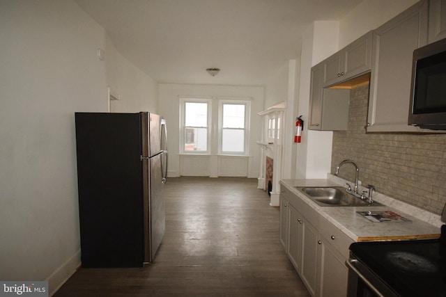 kitchen featuring sink, gray cabinets, decorative backsplash, appliances with stainless steel finishes, and hardwood / wood-style flooring