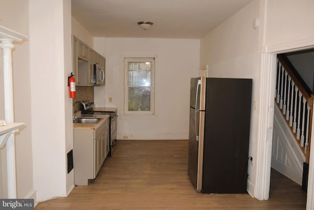 kitchen featuring gray cabinets, decorative backsplash, light hardwood / wood-style floors, and stainless steel appliances