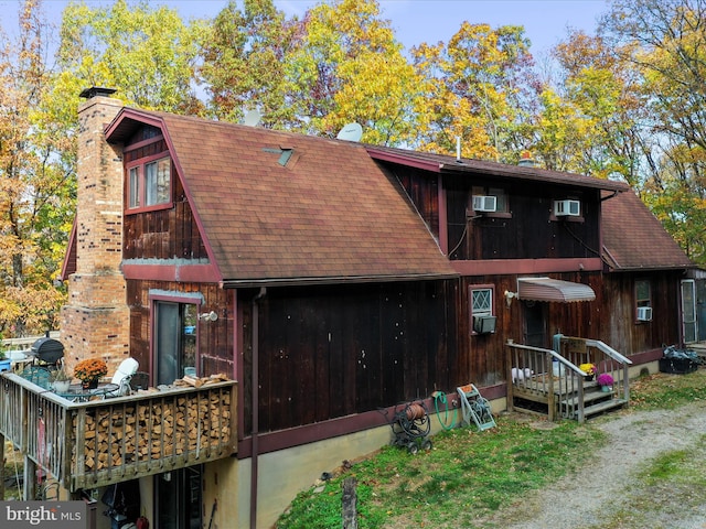 view of front of home with an AC wall unit and cooling unit