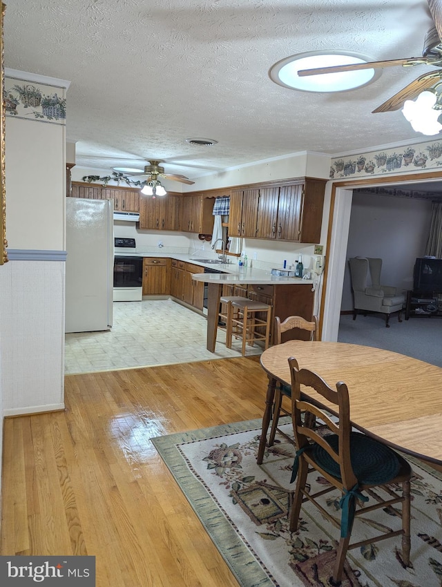 kitchen featuring ceiling fan, white appliances, a textured ceiling, and light hardwood / wood-style floors