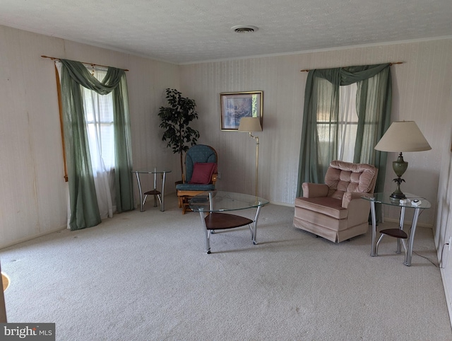 carpeted living room with crown molding, a textured ceiling, and visible vents