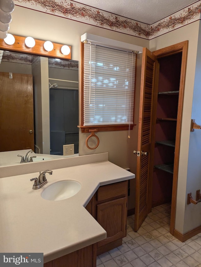 bathroom with tile patterned flooring, vanity, and a textured ceiling