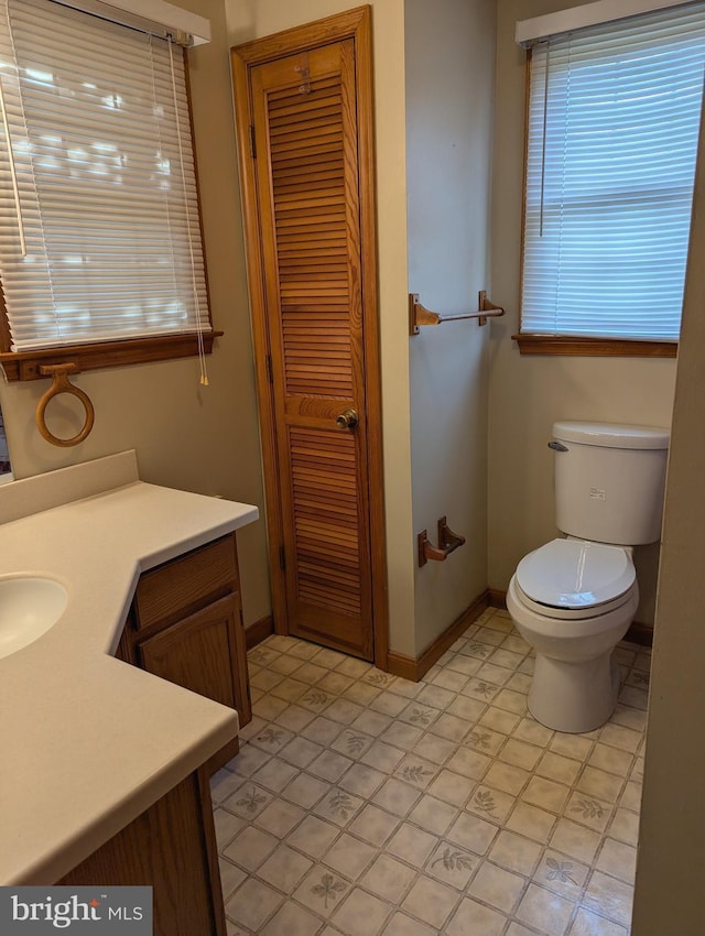 bathroom featuring tile patterned floors, toilet, baseboards, and vanity
