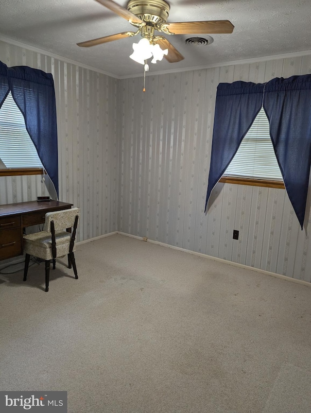 unfurnished office with a textured ceiling, carpet, ornamental molding, and ceiling fan