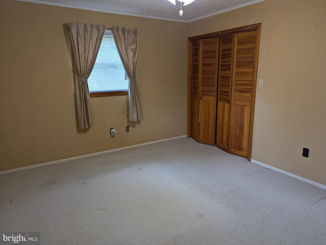 unfurnished bedroom featuring baseboards, ornamental molding, a closet, and carpet