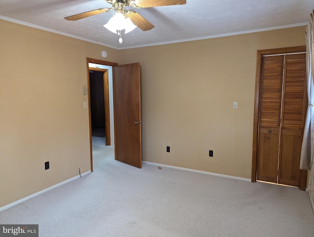 carpeted empty room with ceiling fan, a textured ceiling, and crown molding