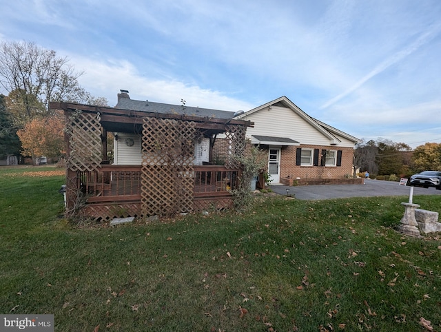 rear view of house featuring a yard, a chimney, and brick siding