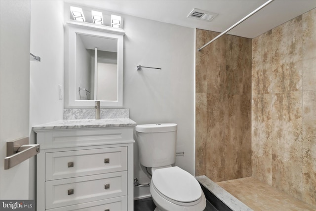 bathroom featuring vanity, toilet, and tiled shower