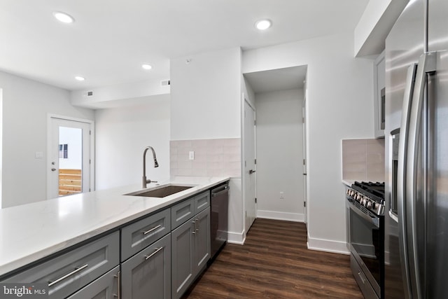 kitchen featuring stainless steel appliances, sink, backsplash, gray cabinetry, and dark hardwood / wood-style flooring