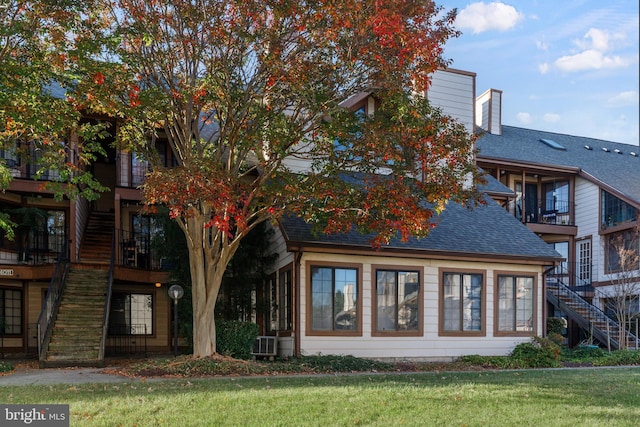 rear view of house with central AC unit, a sunroom, and a yard