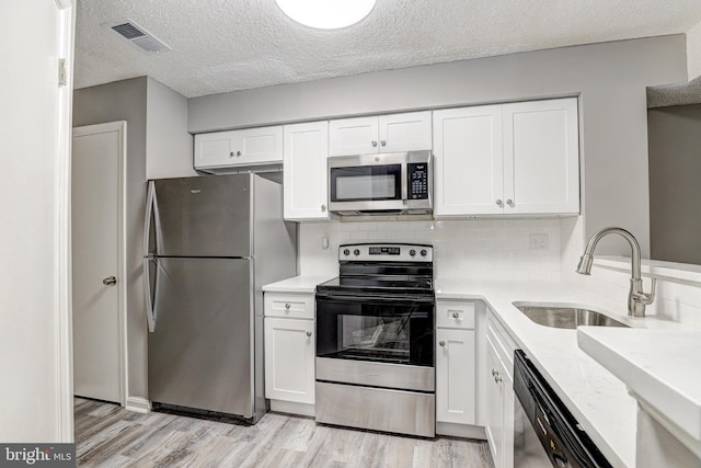 kitchen featuring stainless steel appliances, sink, a textured ceiling, light hardwood / wood-style flooring, and white cabinets