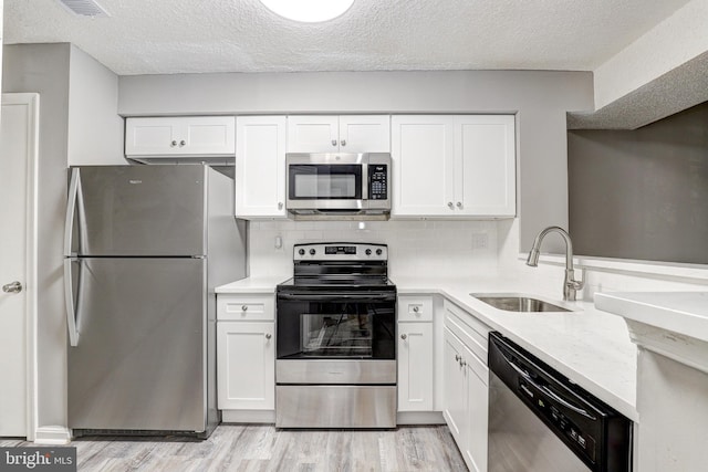 kitchen with stainless steel appliances, light hardwood / wood-style floors, white cabinets, and sink