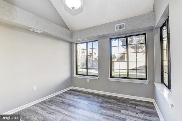 unfurnished room with wood-type flooring, a textured ceiling, and vaulted ceiling