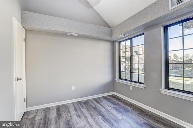 spare room with wood-type flooring, a textured ceiling, and vaulted ceiling