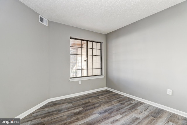 unfurnished room featuring dark hardwood / wood-style flooring and a textured ceiling